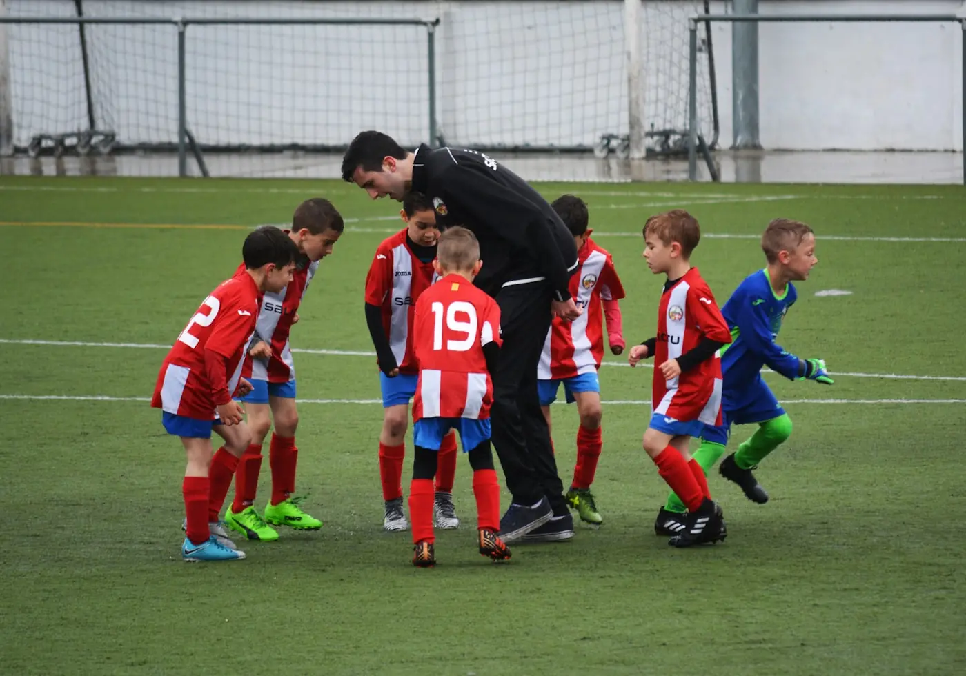 A coach reviewing notes at the sideline of a training session.